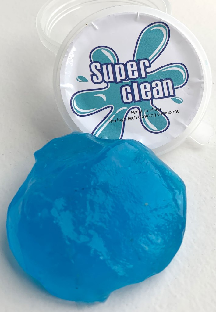 Photo shows a container with the label Super Cleaner. The container is open and a blue blob of goo sits next to it. This goo is the cleaning stuff.